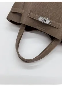 Gros plan d'un sac à main en cuir marron avec un fermoir rotatif en métal argenté