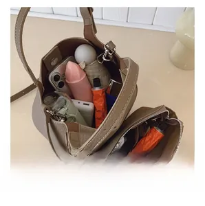 Vue intérieure du sac seau en cuir grainé montrant l'espace de rangement et la pochette