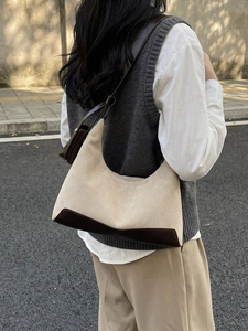 Chic beige suede and brown leather hobo shoulder bag shown in an outdoor street style