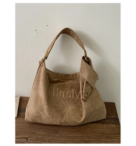 Detail of camel suede tote bag with daisy embroidery and wide shoulder strap