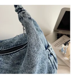 Detail showing soft denim texture and knotted handle of the vintage crossbody bag
