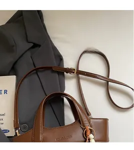 Detail der braunen Leder-Eimertasche mit Tragegriffen und verstellbarem Schultergurt