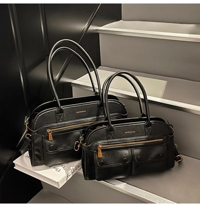 Detail view of large and small black leather Boston bags with golden zipper and logo