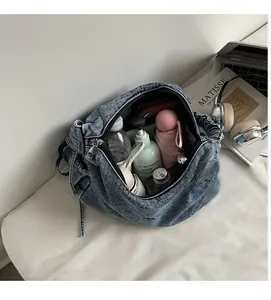 Close-up of the spacious interior of a blue denim crossbody bag with daily essentials