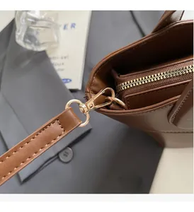Detailansicht der dunkelbraunen Lederhandtasche mit goldenen Metallbeschlägen und Reißverschluss