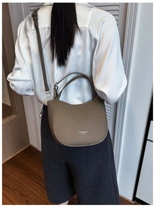Détail du cuir grainé texturé et de la bandoulière réglable sur ce sac seau de ton neutre