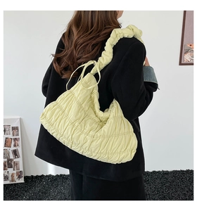 Detail of light yellow pleated cloud tote bag with ruffled shoulder strap on model