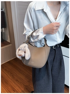 Détail du sac demi-lune en cuir kaki avec charm lapin en peluche gris et boucle