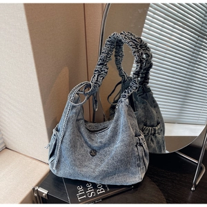 Detail of washed denim hobo bag with ruffled shoulder strap and drawstring sides