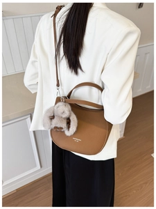 Détail du sac à bandoulière en cuir croissant caramel avec un charm lapin en peluche