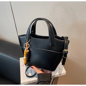Detail der schwarzen matten Leder-Eimertasche mit Holzperlen und Schultergurt