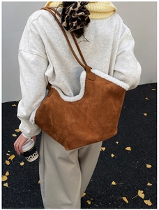 Detail view of brown suede tote bag with white faux fur trim and leather shoulder strap