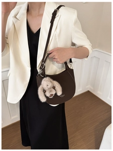 Modèle portant un sac seau demi-lune marron foncé avec breloque lapin et bandoulière