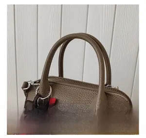 Detail of a brown lychee pattern leather handbag handle with a cute bear charm accent