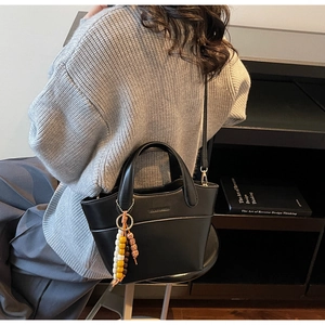 Details des Somerset-Logos an schwarzer Beuteltasche mit bunter Perlenkette und Leder