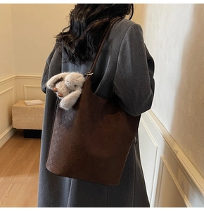 Detail of dark brown woven leather tote bag with a cute plush rabbit pendant charm