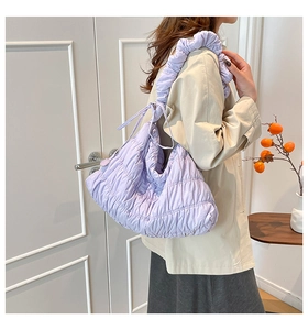 Detail view of purple quilted tote bag with pleated ruffles on shoulder strap