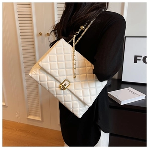 Side view of white quilted shoulder bag with gold chain strap and metal lock