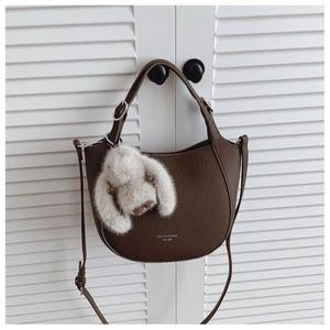 Détail du sac seau en cuir marron à motif litchi avec breloque lapin en peluche
