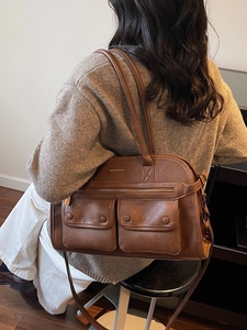 Retro brown leather tote bag with front pockets shown on model in a casual setting