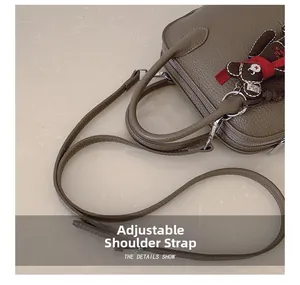 Close-up of brown pebbled leather shell bag with adjustable strap and bear charm