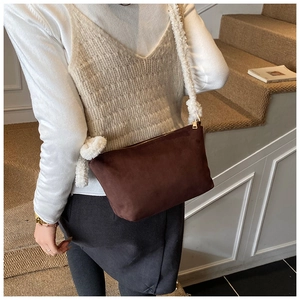 Detail of coffee suede underarm bag with white sherpa shoulder strap and gold zipper closure