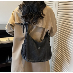 Detail of black denim hobo bag with knotted shoulder strap and side pocket design