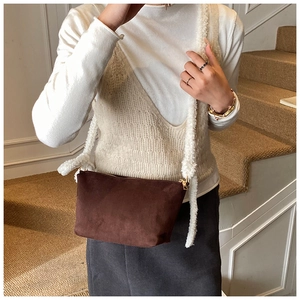 Detail of a dark brown suede bucket bag with a soft white faux fur shoulder strap