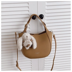 Détail du sac demi-lune marron en cuir grainé avec un charmant lapin en peluche blanc
