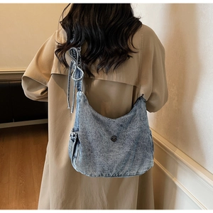Detail of light blue washed denim crossbody bag featuring a stylish bow knot shoulder strap