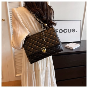Detailed view of the black quilted texture and golden twist-lock closure on chain bag