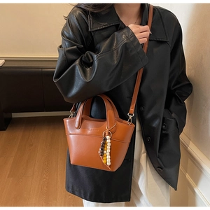 Detailansicht der braunen Bucket Bag mit schickem Perlenanhänger und feinem Riemen