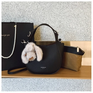 Détail du sac seau en cuir noir avec ferrures argentées et charm lapin en peluche
