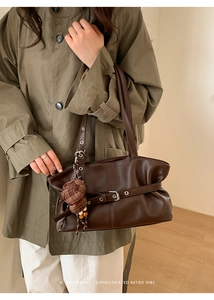 Detail of retro dark brown leather tote with decorative buckle and hat-shaped pendant