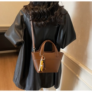 Detail der braunen Eimer-Tasche mit bunten Holzperlen und einem runden Tragegriff
