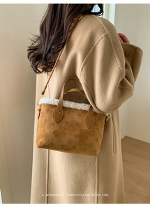 Detail of brown suede bucket bag featuring embossed patterns and white faux fur trim