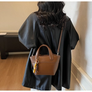 Detail der dunkelbraunen Retro-Beuteltasche mit EDILAR & MISS Logo und Perlenanhänger