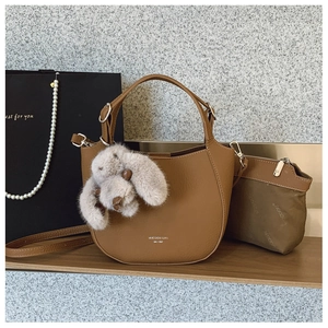 Détail du sac à main en cuir marron avec charm lapin en peluche et logo MUCOOU BAG
