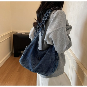Detail of dark blue denim hobo bag featuring ruched shoulder strap and cute bow accents