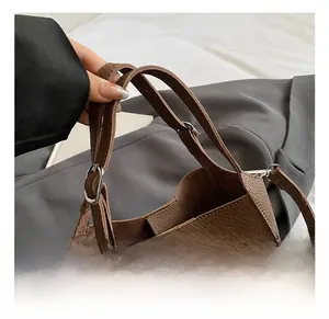 Detail shot of brown lychee-patterned leather texture and sturdy double handles