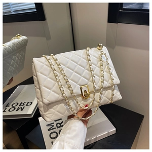 Detail of white quilted crossbody bag with gold chain strap and metallic twist lock closure