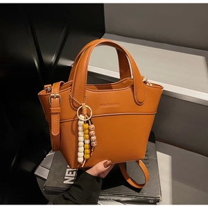 Detailansicht braune Eimertasche mit Retro-Holzperlen auf einem schwarzen Magazin