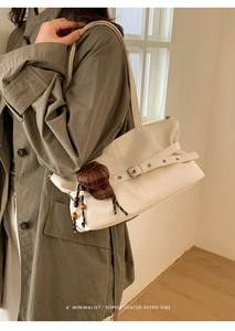 Close-up of minimalist retro tote bag with buckle detail and plaid mini-hat pendant decoration