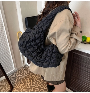 Détail d'un sac hobo matelassé noir en nylon, porté à l'épaule sur un mannequin