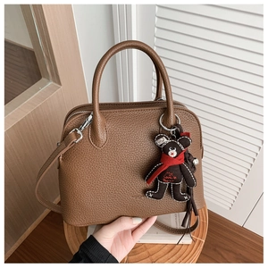 Close-up of dark brown lychee textured leather handbag with a cute lucky bear charm
