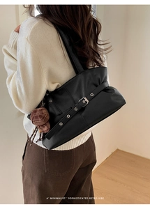 Close-up of black oil wax leather tote bag with vintage metal buckle and mini hat charm