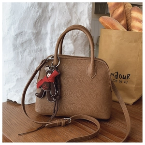 Detailed shot of brown lychee leather shell bag with adjustable strap and bear charm