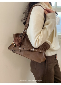 Macro detail of dark brown retro tote bag with buckle straps and plaid hat charm accessory