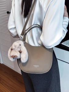 Sac à bandoulière en cuir kaki avec charme lapin en peluche sur chemisier en soie blanc