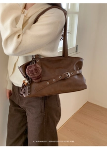 Detail of retro brown tote bag with leather strap, silver buckle and mini hat charm